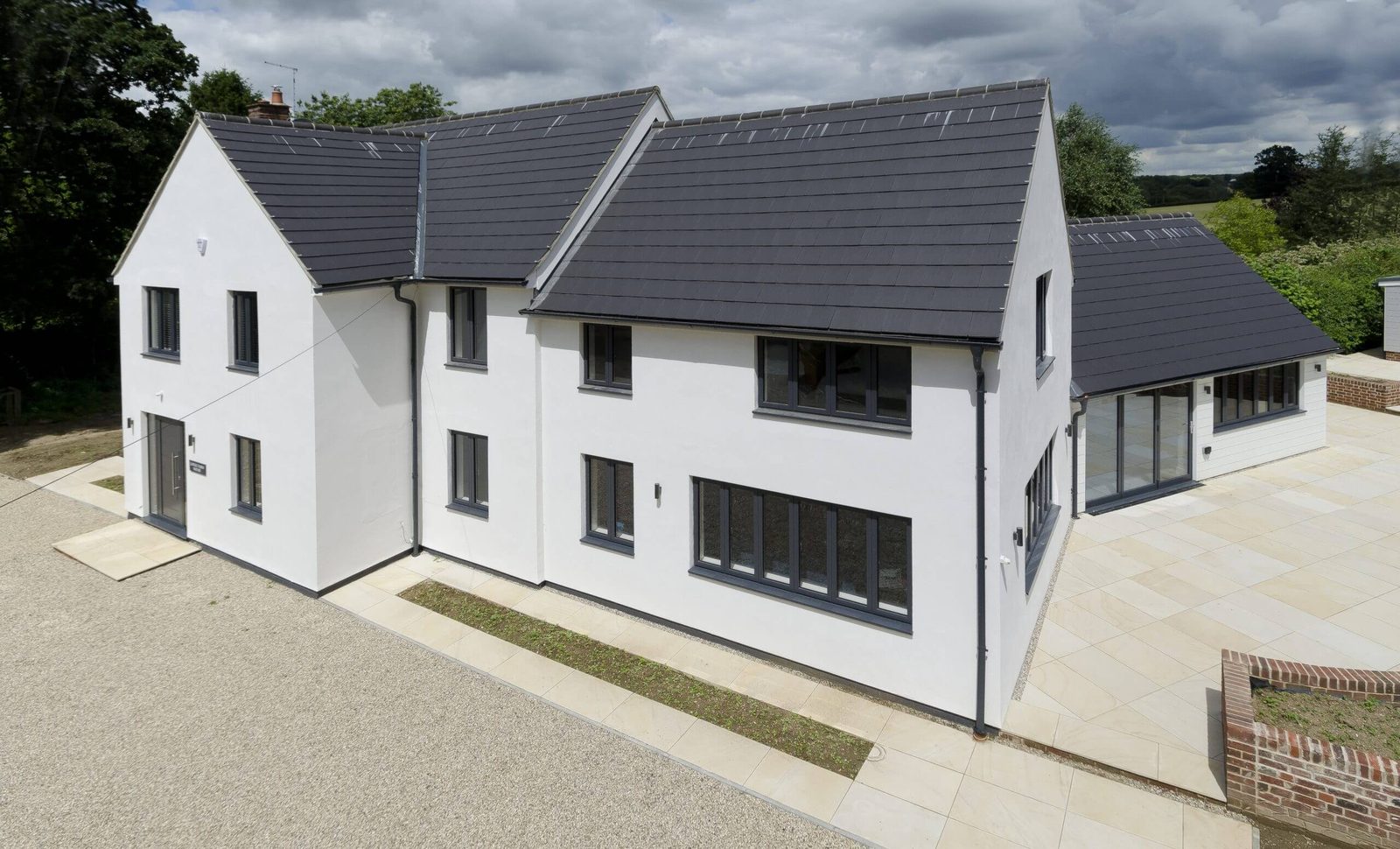 White rendered house with dark tiled roof and guttering