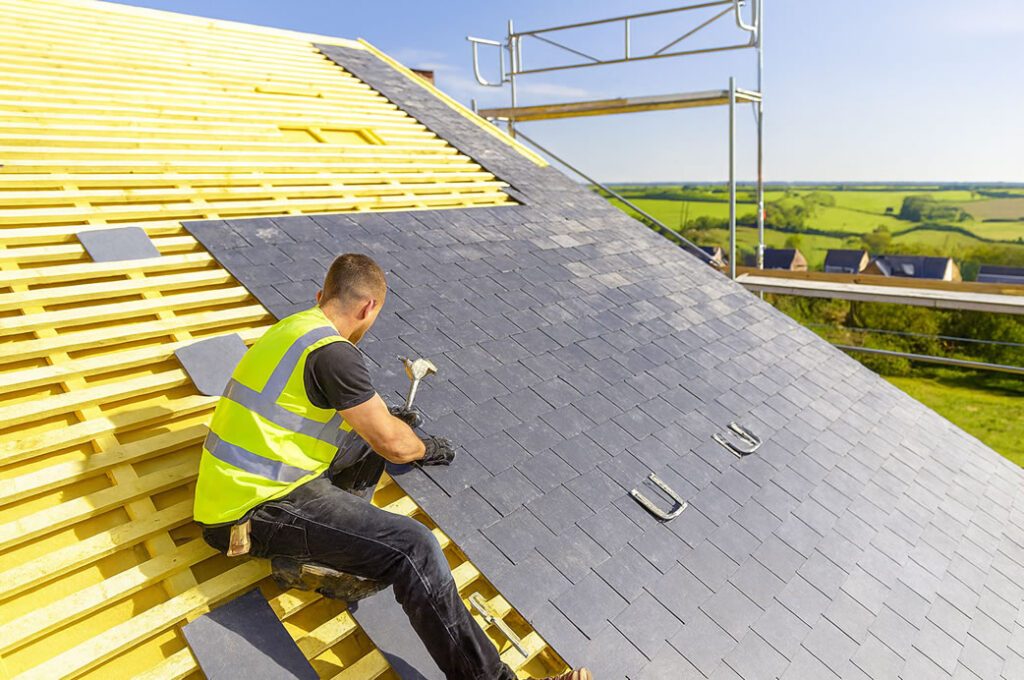 Roofer fitting new roof tiles over breathable membrane